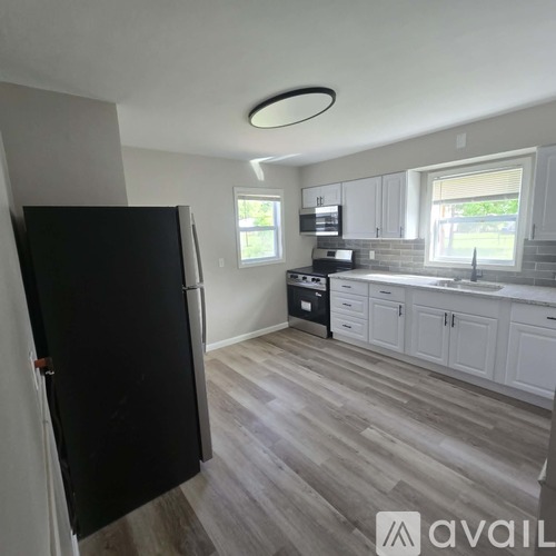 A kitchen with a black fridge and wooden floors.