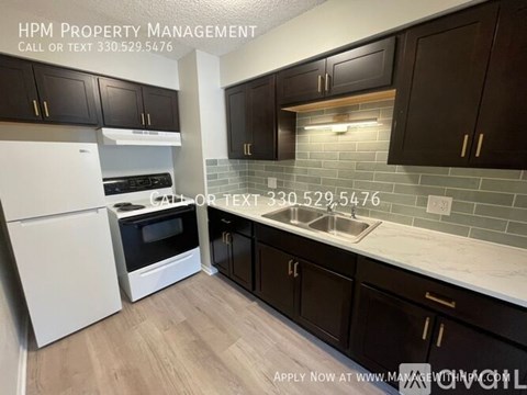 A kitchen with dark brown cabinets and a white refrigerator.