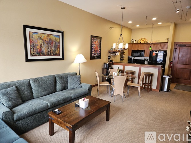 A living room with a grey couch, a coffee table, and a bar area with a television.