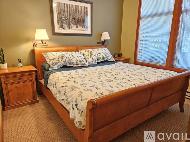 A bedroom with a bed, nightstand, and a painting on the wall.