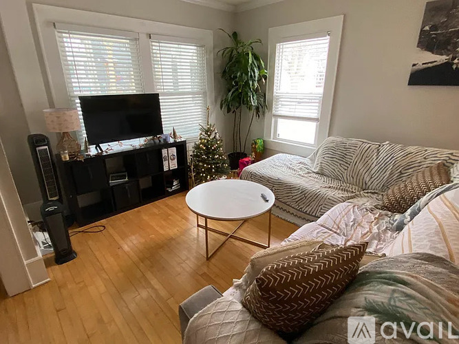 A living room with a couch, a coffee table, a television, and a Christmas tree.
