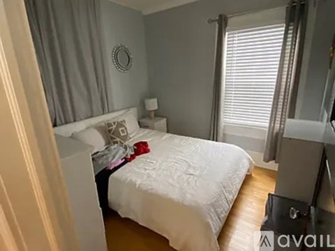 A bedroom with a white bed and a grey wall.