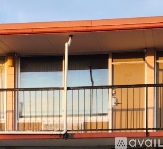 A balcony with a metal railing and a window overlooking the beach.