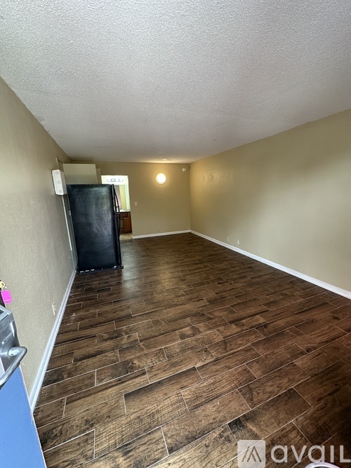 A room with wooden flooring and a black refrigerator.