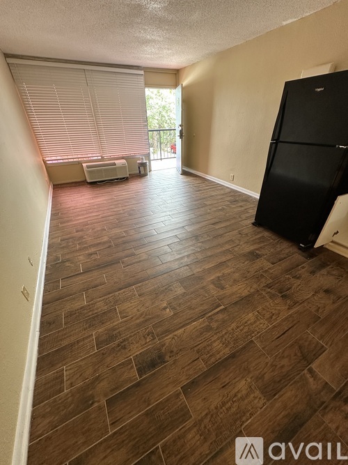 A kitchen area with a black fridge and wooden flooring.