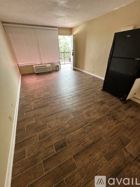 A kitchen area with a black fridge and wooden flooring.
