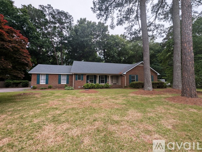 A house with a green lawn and trees in the background.