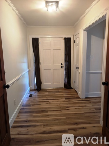 A hallway with a white door and wooden floors.