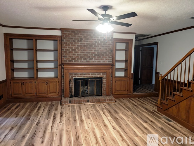 A room with wooden floors and a brick fireplace.