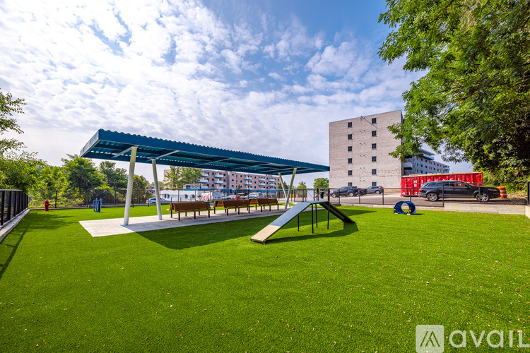 A playground with a green lawn and a blue canopy.
