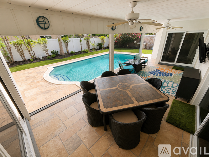 A patio with a table and chairs overlooking a pool.