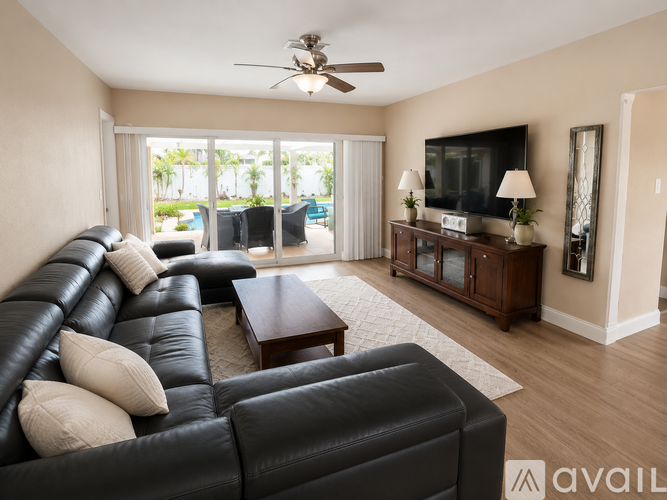 A living room with a black leather couch and a flat screen TV on a wooden cabinet.