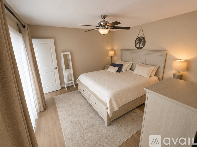 A bedroom with a large bed, a ceiling fan, and two lamps.