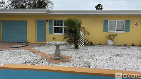 A yellow house with a blue door and a pool in front.