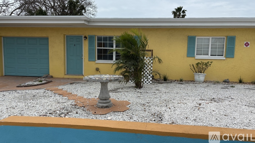 A yellow house with a blue door and a pool in front.