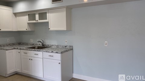 A kitchen with white cabinets and a granite countertop.