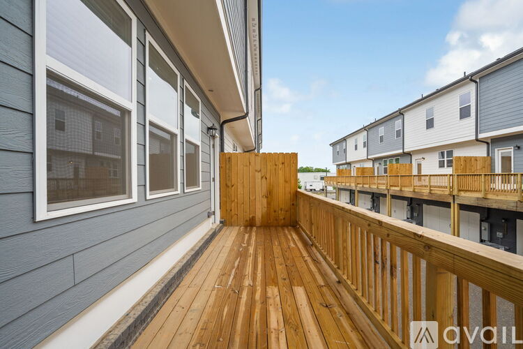 A wooden deck leads to a building with a balcony.