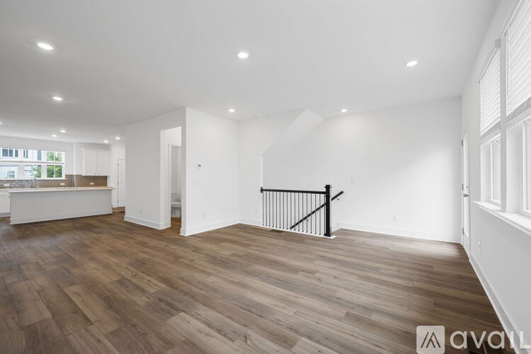 A spacious room with wooden flooring and white walls.
