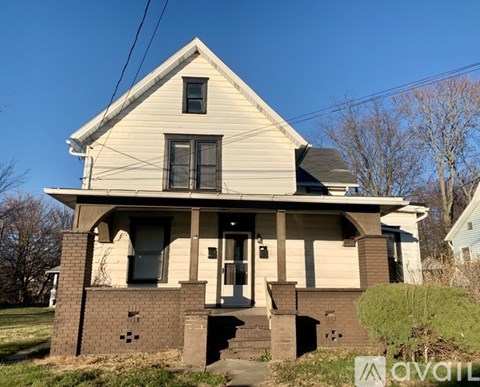 A house with a beige siding and a brick foundation is for sale.