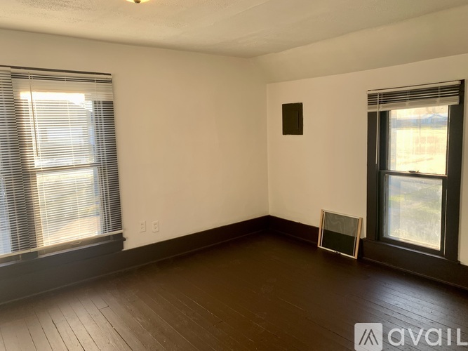 A room with wooden floors and two windows.