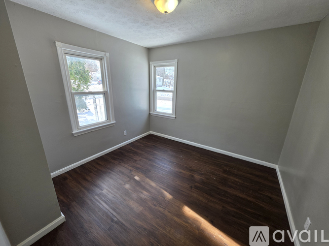 A room with wooden floors and two windows.