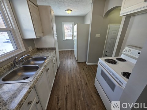 A kitchen with a stove, sink, and cabinets.