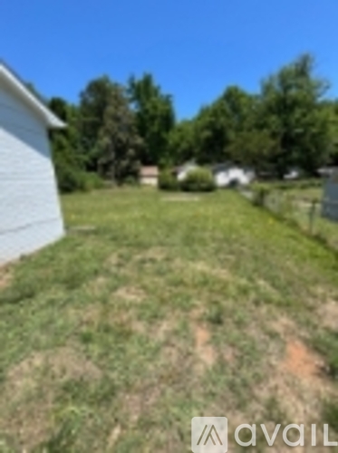 A grassy area in front of a house with a clear blue sky.