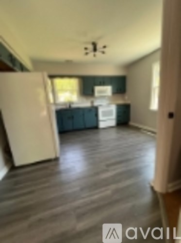 A kitchen with a white refrigerator and wooden floors.