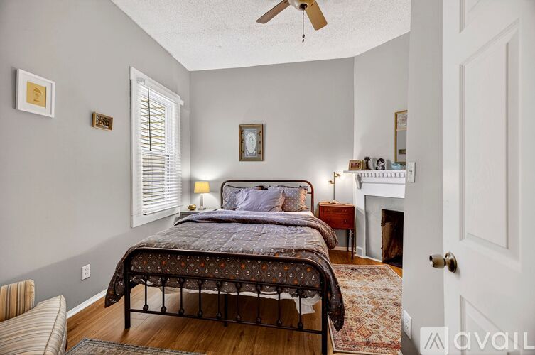 A bedroom with a bed, a chair, and a fireplace.