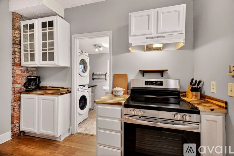A kitchen with white cabinets and a brick wall.