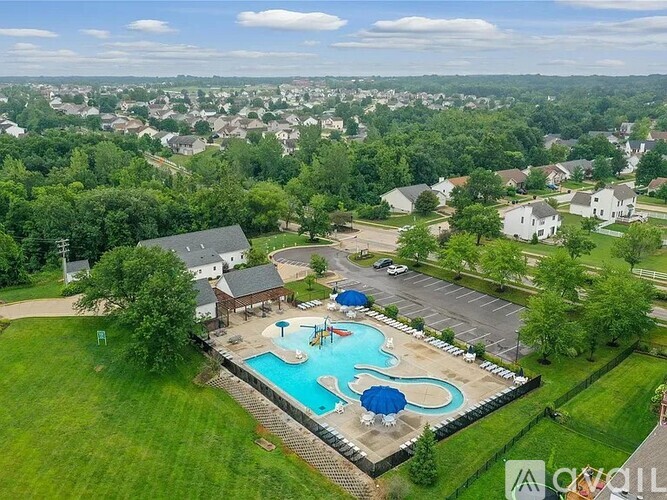 A pool with a slide and a waterfall in the middle of a grassy area.