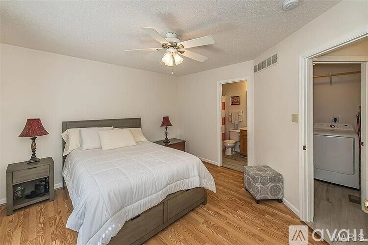 A bedroom with a bed, two lamps, and a ceiling fan.