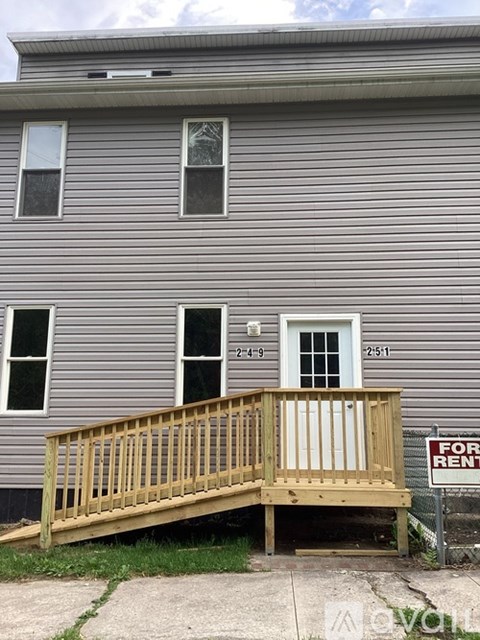 A grey house with a wooden deck in front.