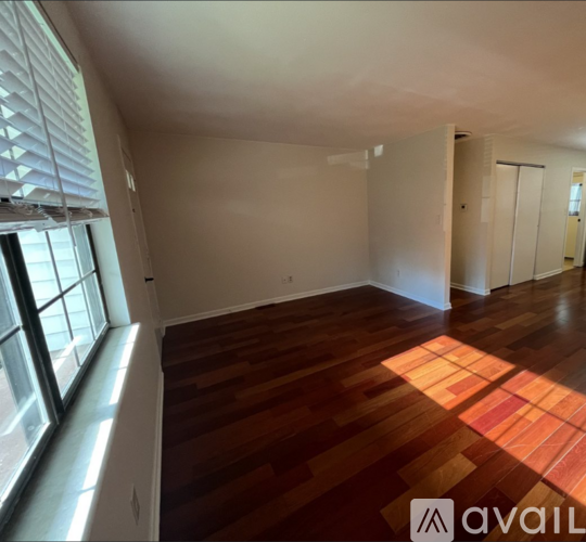 A room with wooden flooring and white walls is available for rent.