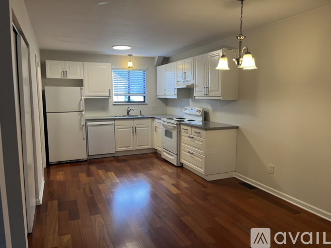A kitchen with white appliances and wooden floors.