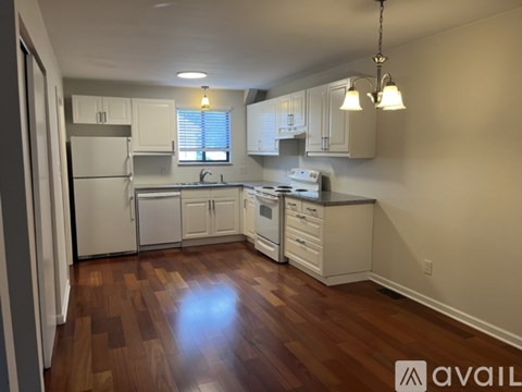A kitchen with white appliances and wooden floors.