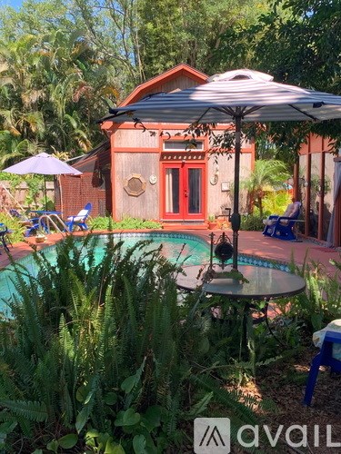 A pool area with a table and chairs and a house in the background.