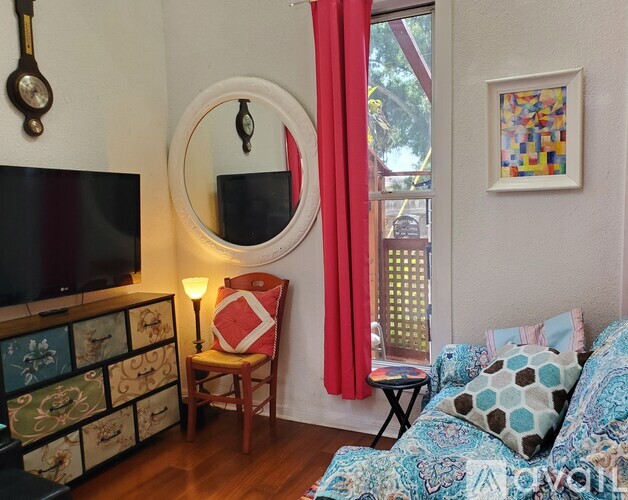 A living room with a blue couch and a round mirror on the wall.