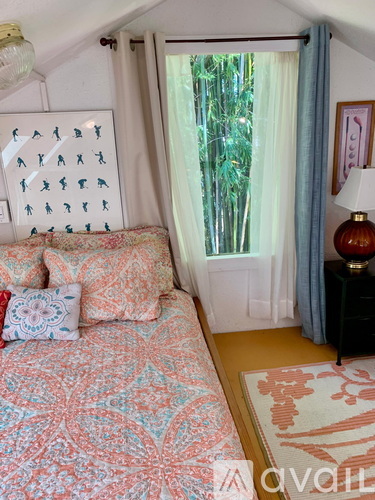 A bedroom with a bed, a lamp, and a window with curtains.