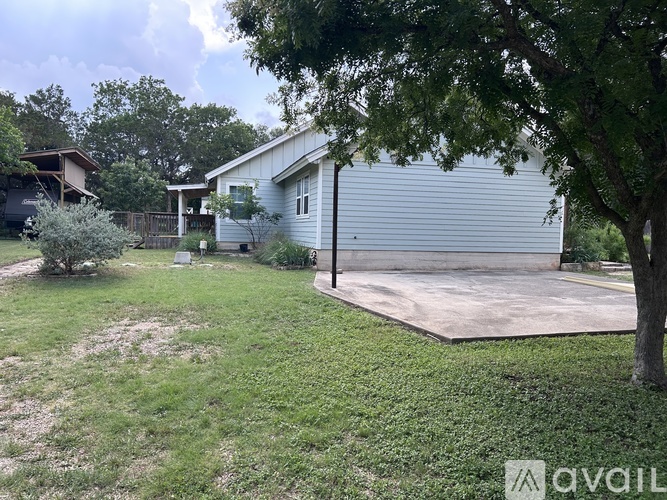 A backyard with a house, a tree, and a concrete slab.