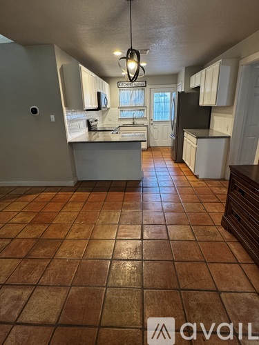 A kitchen with tile flooring and a hanging light fixture.