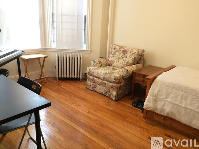 A room with a floral chair and a wooden bed.