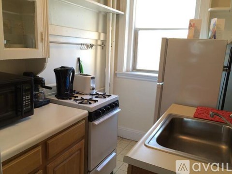 A kitchen with a white refrigerator, black microwave, and a white stove top oven.