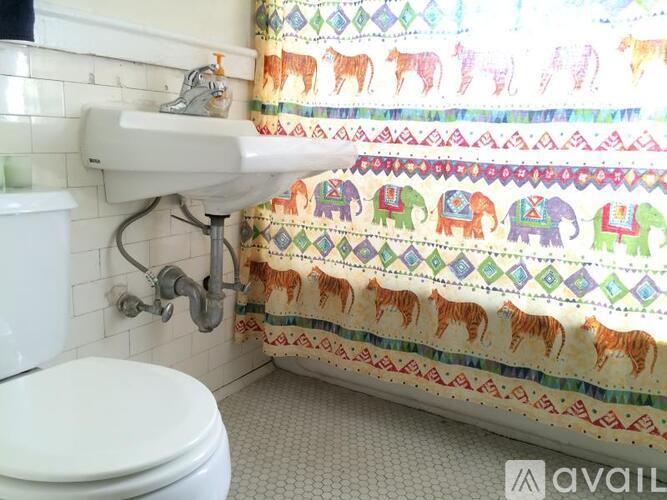 A bathroom with a white toilet, a white sink, and a shower curtain with elephants on it.