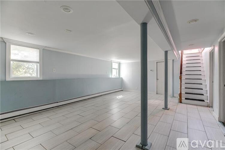 A spacious room with a tiled floor and a staircase on the right side.