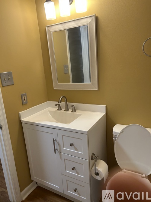 A bathroom with a sink, toilet, and mirror.