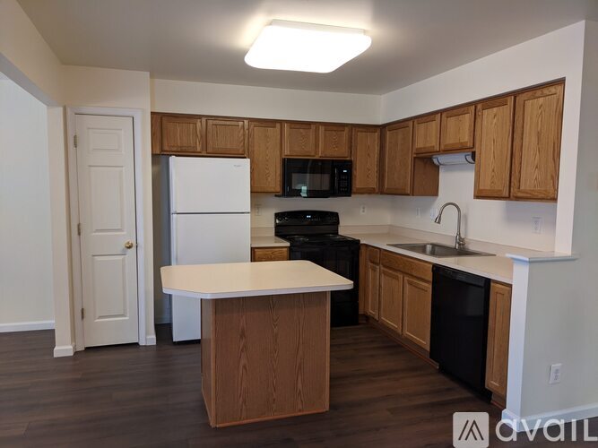A kitchen with wooden cabinets and a white island.