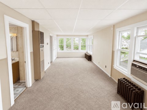 A spacious room with carpeted floor and large windows.