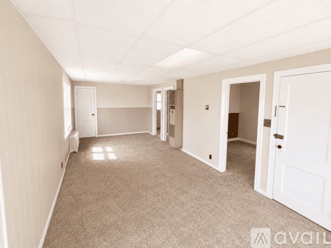 A spacious room with white walls and carpeted floor.
