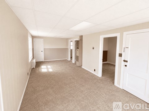 A spacious room with white walls and carpeted floor.